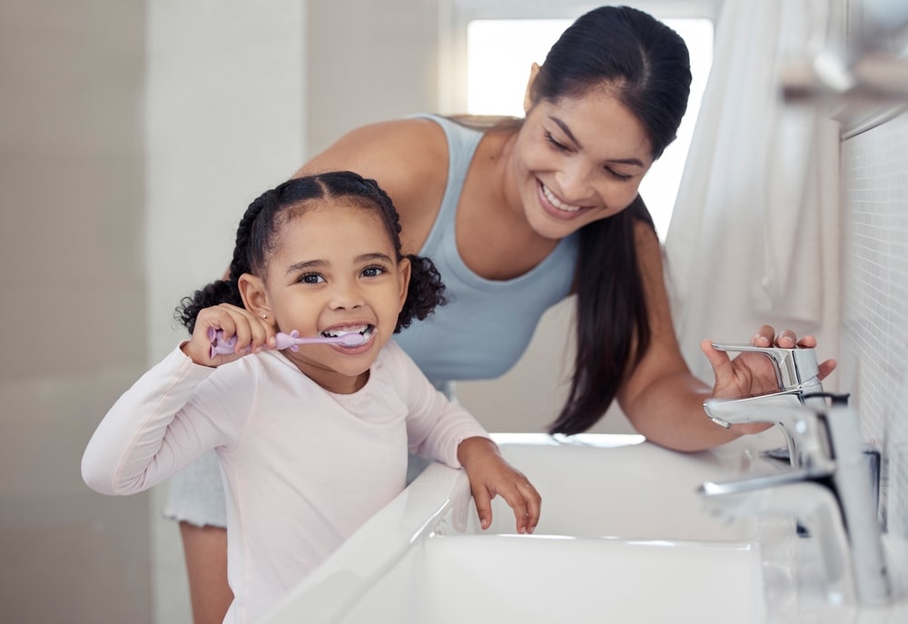 Un mère supervise son enfant pendant le brossage des dents