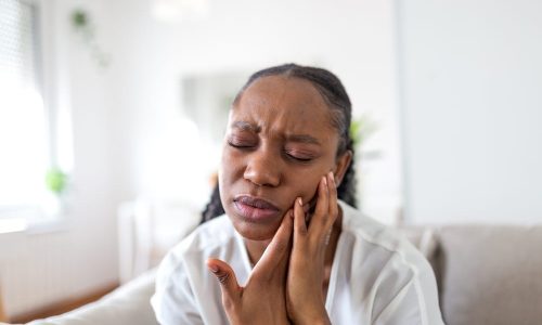 Une femme présente une rage de dents comme urgence dentaire